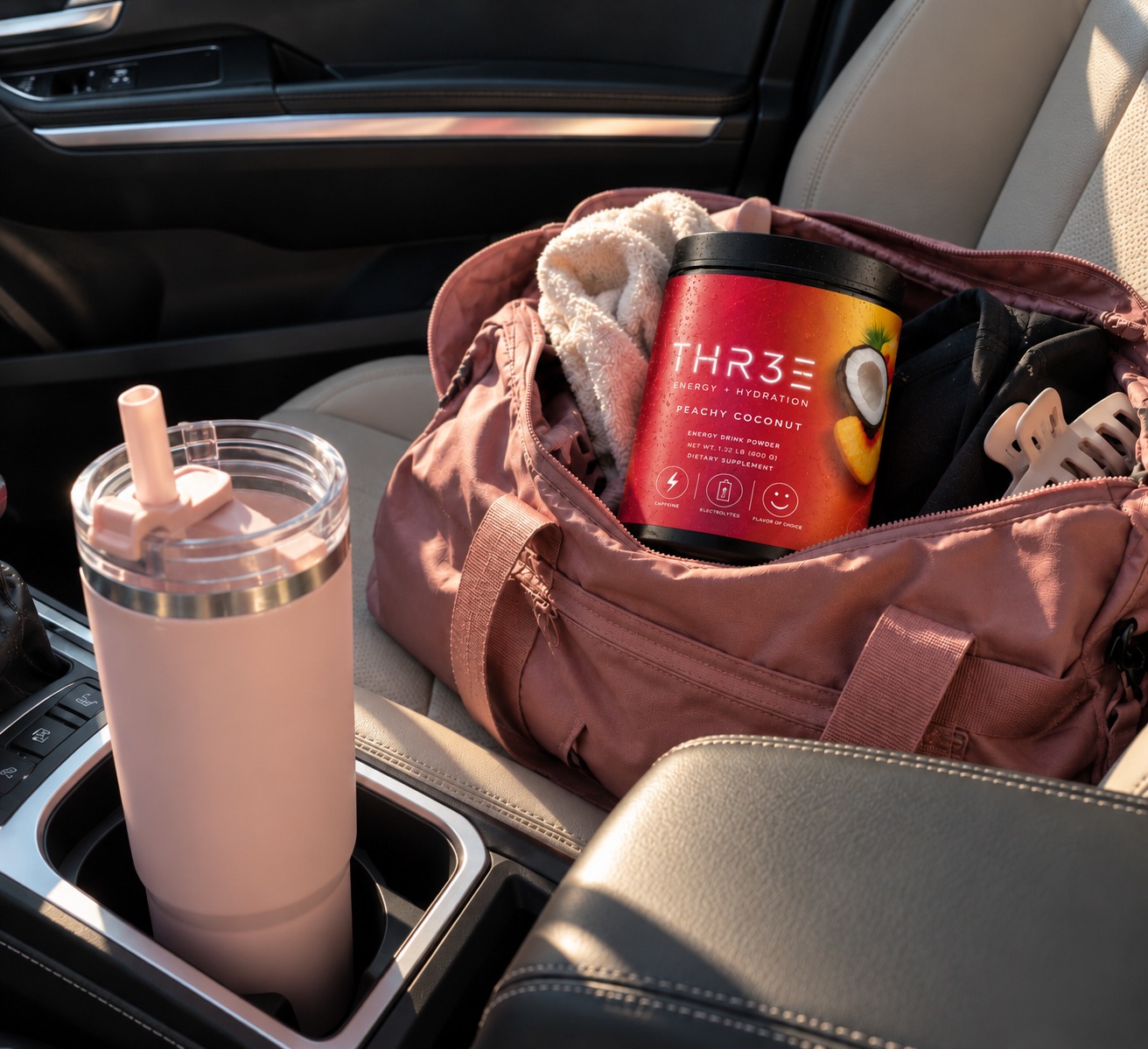 THR3E Peachy Coconut tub in a gym bag next to a pink tumbler in a car cup holder